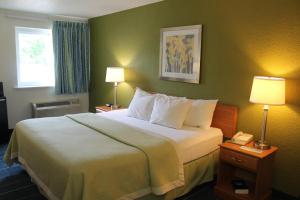 a hotel room with a bed with two lamps and a phone at Days Inn & Suites by Wyndham Bridgeport - Clarksburg in Bridgeport +34 photos
