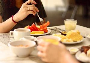 Hotel Saint Paul في ماناوس: شخص يأكل الطعام على طاولة مع أطباق من الطعام