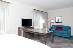 Habitación de hotel con escritorio y sofá azul en Hampton Inn & Suites by Hilton Chicago Schaumburg IL, en Schaumburg