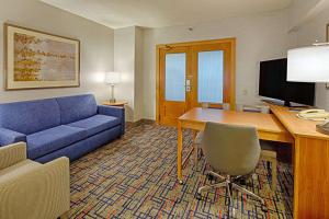 a living room with a blue couch and a desk with a computer at Embassy Suites by Hilton Chicago O'Hare Rosemont in Rosemont