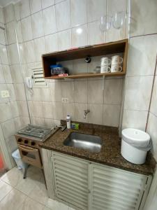 Il comprend une petite cuisine équipée d'un évier et d'une cuisinière. dans l'établissement Lindo kit na quadra da praia, à Santos