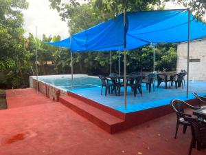 einen Pool mit Tischen und Stühlen und einem blauen Sonnenschirm in der Unterkunft Hotel Chulamar, Piscina y Restaurante in Escuintla