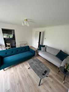 ein Wohnzimmer mit einem blauen Sofa und einem Tisch in der Unterkunft Flat 1 Hobart Lodge in Hendon