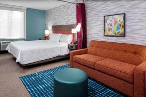 a hotel room with a bed and a couch at Home2 Suites By Hilton North Charleston University Blvd in Charleston