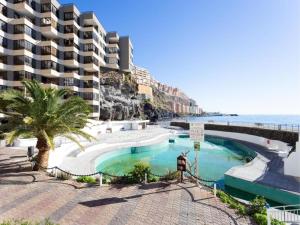 a swimming pool next to the ocean with a building at Live Tabaiba Maritime Avenue con vista del mar in Tabaiba