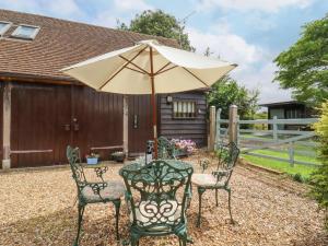 einen Terrassentisch mit Sonnenschirm und Stühlen in der Unterkunft The Studio, Horseshoe Cottage in Fulbourn