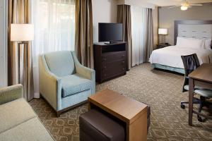 um quarto de hotel com uma cama e uma cadeira e uma televisão em Homewood Suites by Hilton Cleveland-Solon em Solon