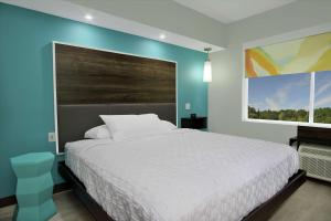 - une chambre avec un lit blanc et un mur bleu dans l'établissement Tru by Hilton Bryan College Station, à Bryan