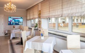 ein Esszimmer mit Tischen, einem TV und Fenstern in der Unterkunft Prohipo Stables & LMC - Premium Rooms 