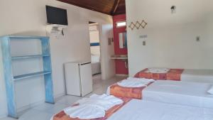 a room with two beds and a tv on the wall at Pousada Varanda do Sol in Arraial d'Ajuda