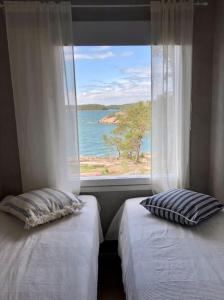 two beds with pillows in front of a window at Klippan - mökki omalla rannalla Nauvossa in Nauvo