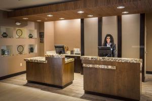 a woman standing at a counter in a hotel lobby at Homewood Suites by Hilton Charlotte Ballantyne, NC in Charlotte