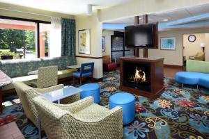 a lobby with a fireplace and chairs and a tv at Hampton Inn Charlotte North Lake Norman in Cornelius