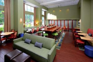 a restaurant with a couch and tables and chairs at Hampton Inn & Suites Huntersville in Huntersville