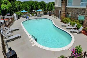 a large swimming pool with chairs and a building at Hampton Inn & Suites Huntersville in Huntersville