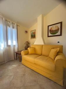 um sofá amarelo numa sala de estar com uma mesa em Venti di Vacanza - Levante & Grecale em Olbia