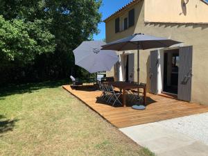 a wooden deck with a table and two umbrellas at Villa et chalet avec piscine proche Aix & Luberon in Peyrolles-en-Provence