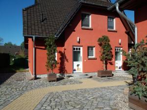 a red house with two trees in front of it at Ferienhaus-Windflüchter Hirtenweg 3B in Zingst