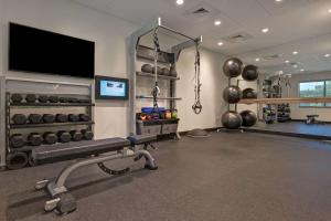 a gym with a bench and a flat screen tv at Tru By Hilton Mooresville in Mooresville