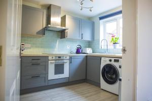 a kitchen with blue cabinets and a washing machine at Beautiful House in Stratford upon Avon in Stratford-upon-Avon