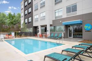 une piscine avec des chaises et un bâtiment dans l'établissement Tru By Hilton Rock Hill, SC, à Rock Hill