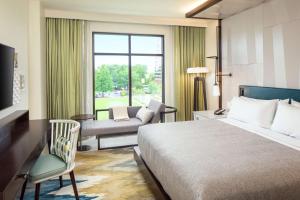 um quarto de hotel com uma cama e uma cadeira e uma janela em Canopy By Hilton Charlotte SouthPark em Charlotte