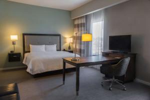 a hotel room with a bed and a desk with a television at Hampton Inn & Suites Charlotte/Ballantyne, Nc in Charlotte