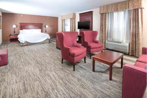 a hotel room with a bed and red chairs at Hampton Inn & Suites Greensburg in Greensburg