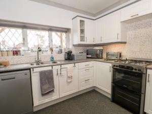 a kitchen with white cabinets and a black stove top oven at 5 Woodside Avenue in Rhyl