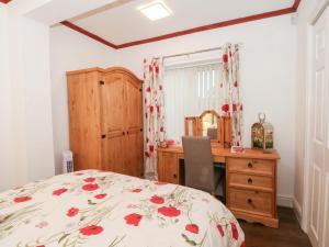 a bedroom with a bed with a dresser and a desk at 5 Woodside Avenue in Rhyl