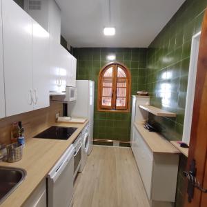 EL COBIJO في Mojados: مطبخ به أجهزة بيضاء وبلاط أخضر