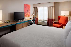 a hotel room with a bed and a chair and a television at Hilton Garden Inn Colorado Springs in Colorado Springs