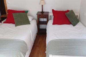 2 Einzelbetten mit roten Kissen in einem Zimmer in der Unterkunft Piso con preciosas vistas, patio privado y amplio garaje in Puentedeume