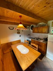 a kitchen with a wooden table and a refrigerator at Casa Cantone Devero-baita storica con balcone e giardino, posizione comoda e soleggiata- spazio biciclette in Alpe Devero