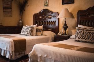 1 dormitorio con 2 camas y mesa con lámpara en Hacienda El Carmen Hotel & Spa, en Portes Gil