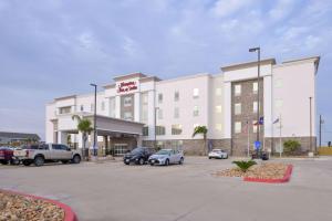 ein großes weißes Gebäude mit Autos auf einem Parkplatz in der Unterkunft Hampton Inn and Suites Port Aransas in Port Aransas