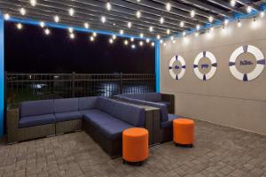 a seating area with a blue couch and orange stools at Tru by Hilton Auburn in Auburn