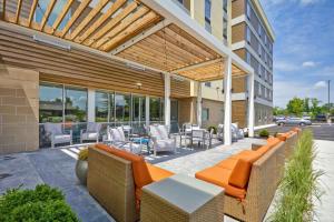 an outdoor patio with orange furniture and tables and chairs at Home2 Suites By Hilton Blue Ash Cincinnati in Blue Ash