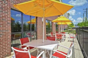 Hampton Inn Blue Ash/Cincinnati, OH في بلو أش: طاولة وكراسي مع مظلة على الفناء