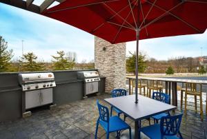 eine Terrasse mit einem Tisch, Stühlen und einem Sonnenschirm in der Unterkunft Home2 Suites By Hilton Springdale Cincinnati in Springdale