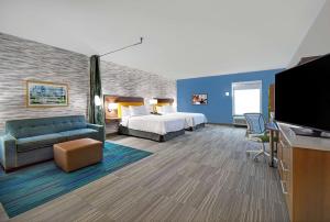 a hotel room with a bed and a flat screen tv at Home2 Suites By Hilton Springdale Cincinnati in Springdale