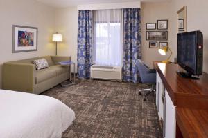 a hotel room with a bed and a couch and a television at Hampton Inn & Suites Wilmington in Wilmington