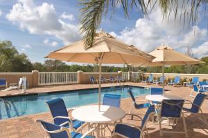 una piscina con mesas, sillas y sombrillas en Hampton Inn & Suites - DeLand, en De Land