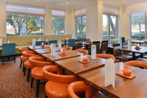 um restaurante com mesas e cadeiras de madeira e janelas em Hilton Garden Inn Addison em Addison