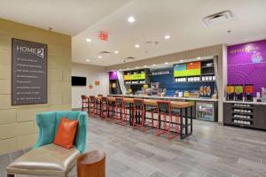a restaurant with a bar with chairs and a counter at Home2 Suites By Hilton McKinney in McKinney