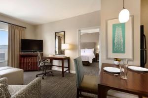 Homewood Suites by Hilton Plano-Richardson في بلانو: غرفة في الفندق مع مكتب وغرفة نوم