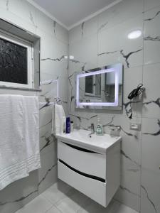 W białej łazience znajduje się umywalka i lustro. w obiekcie Guest house tirana w Tiranie