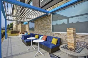a patio with a blue couch and a table and chairs at Tru By Hilton Beavercreek Dayton in Fairborn