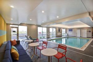 uma sala de piscina com um sofá, mesas e cadeiras em Tru By Hilton Beavercreek Dayton em Fairborn