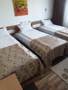 a room with three beds and a table at Hotel Mya in Bistriţa